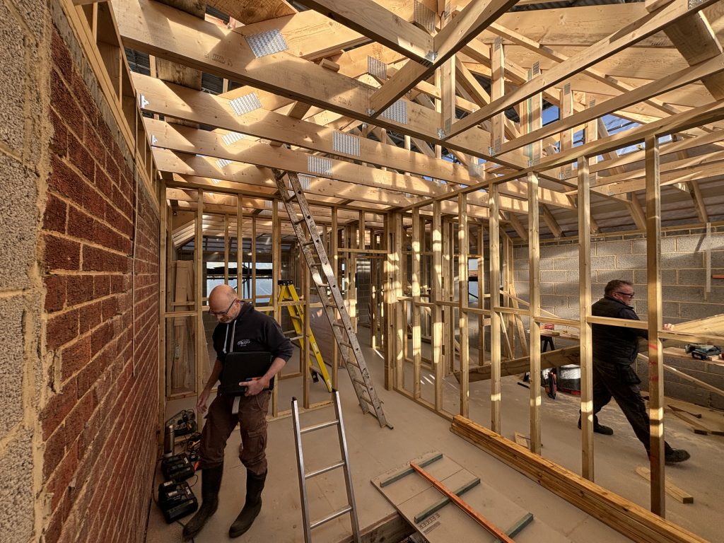 Inside a large house, no roof on, only wooden beams.